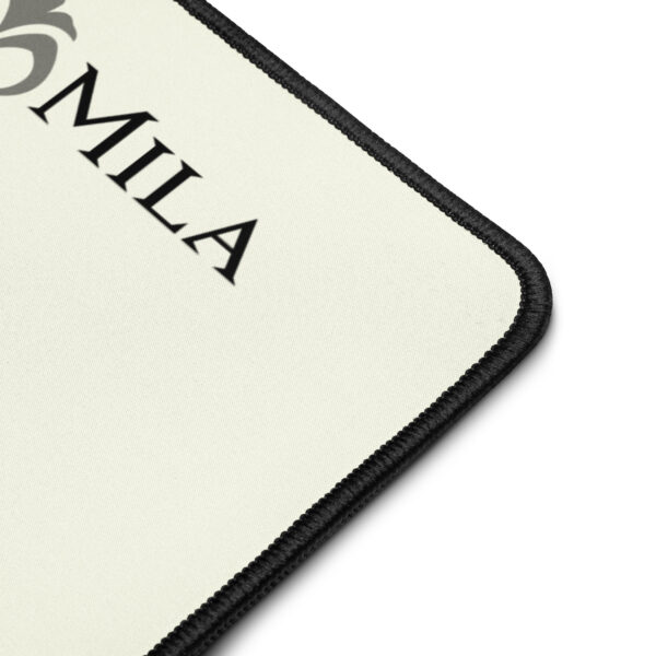 Corner detail of Mila desk mat – stitched edge and logo on soft cream-colored fabric with anti-slip backing