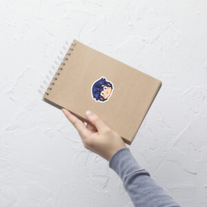 Fire Emblem sticker of Chrom (small, 3x3) applied to a kraft spiral notebook held by one hand.