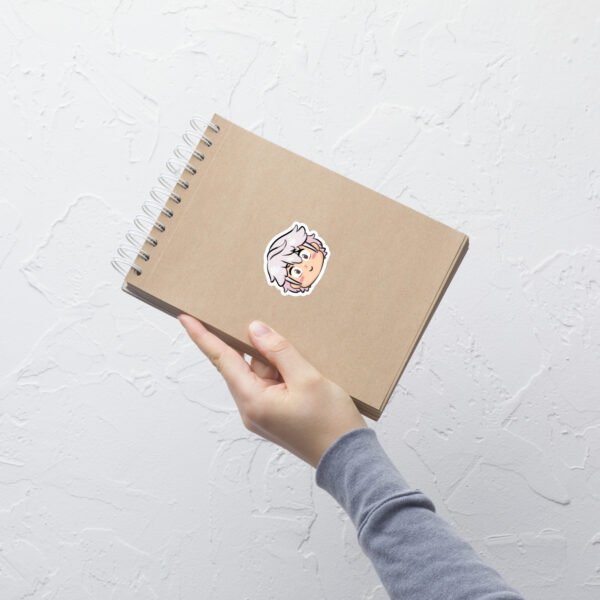 Fire Emblem sticker of Male Robin (small, 3x3) shown on a kraft notebook held in one hand.