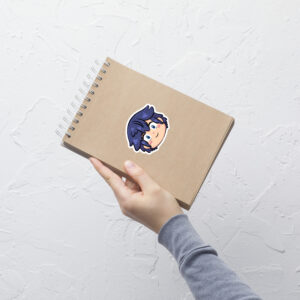 Fire Emblem sticker of Chrom (medium, 4x4) centered on a tan notebook against a white textured wall.