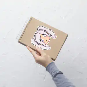 Fire Emblem sticker of Female Robin (large, 5.5x5.5) displayed prominently on a spiral notebook held upright.