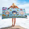 Person holding the blue Fire Emblem Towel wide at the beach, displaying the full Summer Scramble (Ocean) layout with Chrom, Robin, and tropical decorations.