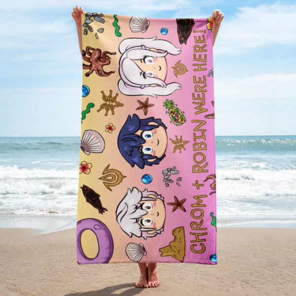 Person holding a Fire Emblem Towel with a vibrant Summer Scramble design on the beach, featuring chibi Chrom and Robin illustrations on a sunset-colored background.