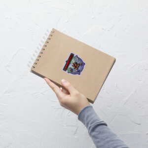 Close-up of a small Fire Emblem Sticker sheet featuring the Lavender Hell Sticker applied to a tan spiral notebook.