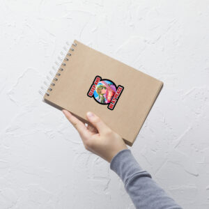 Small Fire Emblem Sticker featuring Adult Tiki applied to a brown spiral notebook, held in one hand.