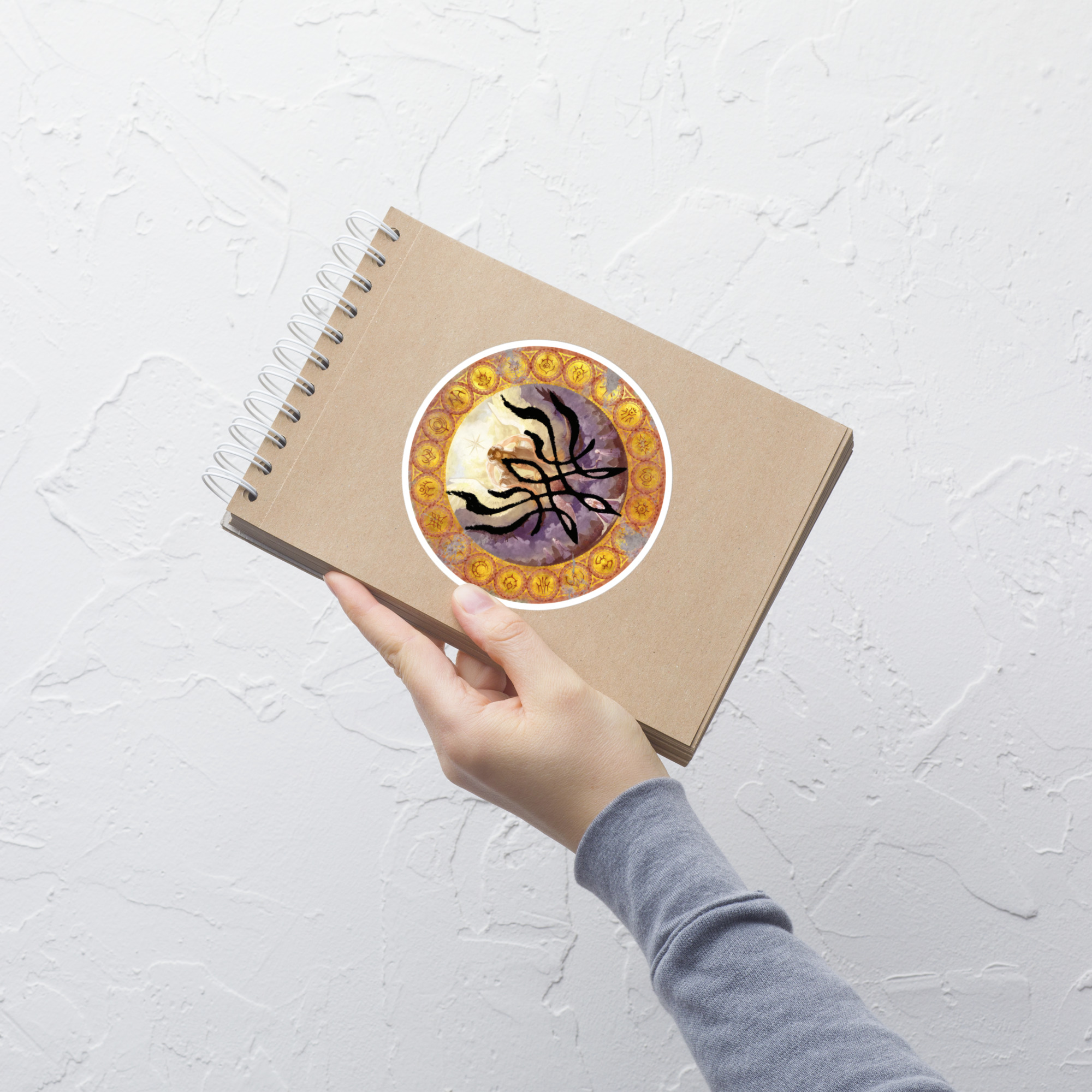 Goddess Crest - Sticker Fire Emblem Sticker with Goddess Crest inspired circular design on notebook, angled lifestyle view