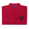 Folded red Fire Emblem polo with black Grimleal symbol embroidered on the chest