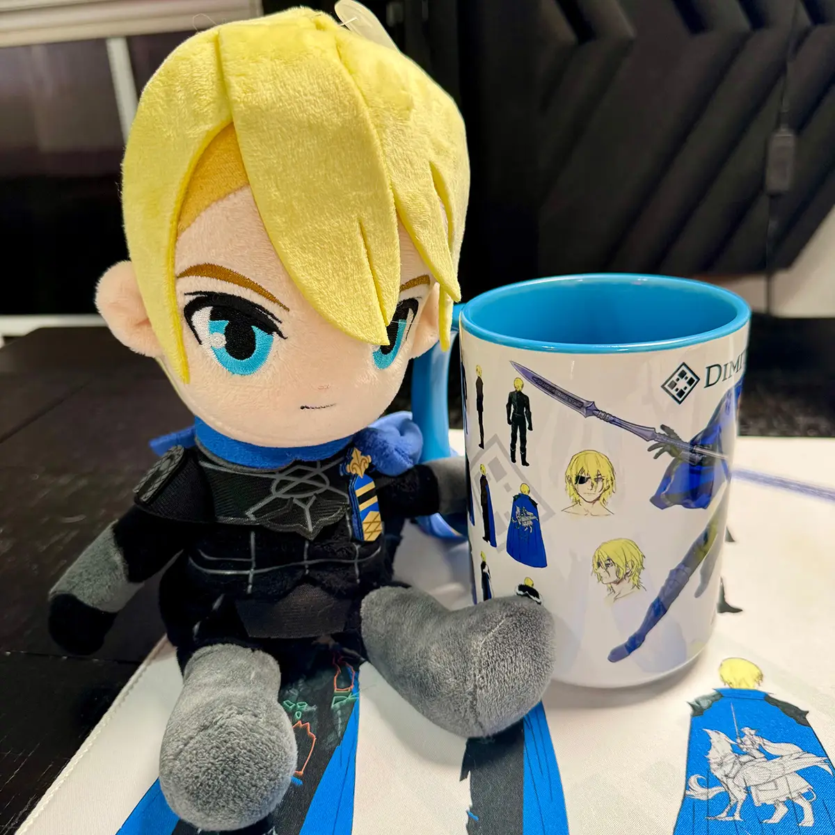 Dimitri plushie sitting beside a matching Fire Emblem concept art mug with a blue interior and handle.